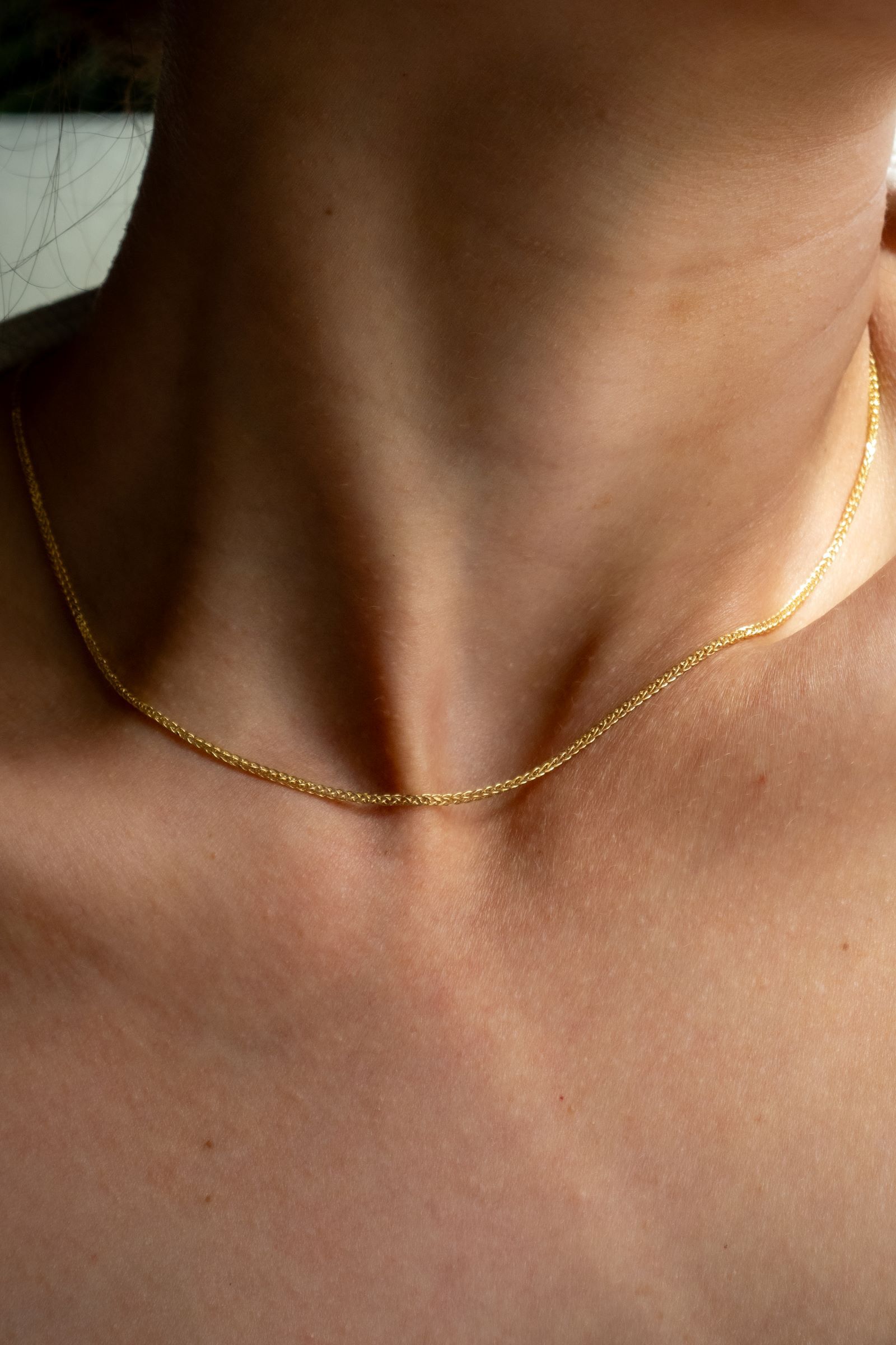 Woman wearing a delicate yellow gold wheat chain Woman wearing a delicate yellow gold wheat chain